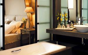 a bathroom with a sink and a bed in the background at Asia Gardens Hotel & Thai Spa, a Royal Hideaway Hotel in Finestrat