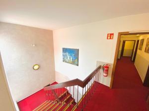 a room with a staircase with a red floor and a stair case at Hotel Grimm in Kassel