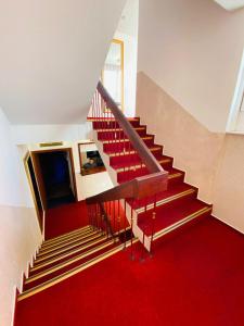 un escalier avec un tapis rouge et un sol rouge dans l'établissement Hotel Grimm, à Cassel