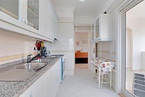 ヴィラモウラにあるVilamoura Main Avenue by Homingの白いキャビネットとシンクのあるキッチン