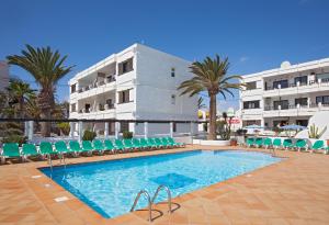 a swimming pool with chairs and a building at Costa Luz Apartment PDC with Sea Views in Tías