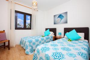Un dormitorio con dos camas con sábanas azules y blancas. en Costa Luz 5 Trioblancos, en Tías