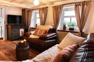 a living room with a leather couch and a television at Ferienhaus Lilace in Böttingen