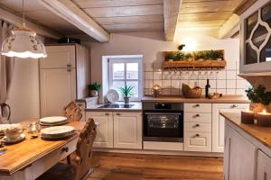 cocina con armarios blancos y mesa de madera en Ferienhaus Lilace, en Böttingen