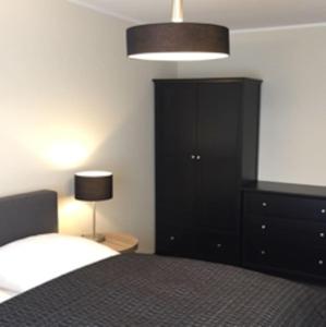 a bedroom with a bed and a black cabinet and a lamp at Gästehaus Ritter & Pacia, Ferienwohnung 2. Etage in Sangerhausen