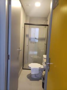 uma casa de banho com um WC e uma porta de duche em vidro. em Unity Hotel - Vila Mariana SP em São Paulo