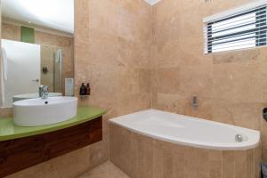 a bathroom with a white tub and a sink at MyPond Stenden Hotel in Port Alfred