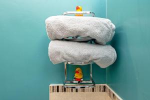 a stack of towels and two rubber ducks on a shelf at Llys Awel in Llangadwaladr +15 photos