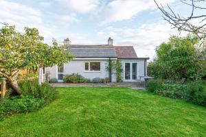 a white house with a lawn in front of it at Llys Awel in Llangadwaladr