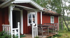 a red cottage with a table and chairs on the porch at Schwedentraum Varpstugan in Kisa