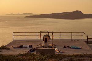 a group of people laying on the ground near the water at Coco-Mat Hotel Santorini in Akrotiri