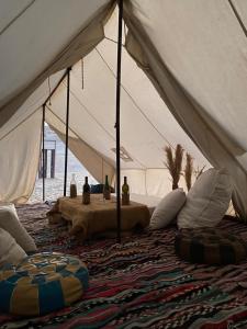 Tzila Camp في الفيوم: خيمة بيضاء فيها مخدات وطاولة فيها