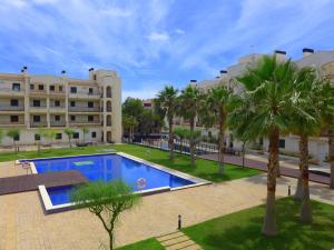 Una piscina con palmeras frente a un edificio. en Rentalmar Residencial La Cala, en Miami Platja