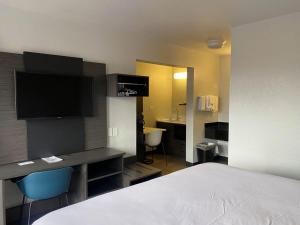 a hotel room with a bed and a desk with a television at Studio 6 Albuquerque NM Midtown in Albuquerque