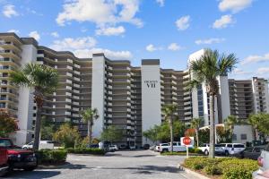 a large apartment building with palm trees in a parking lot at Phoenix 7 215 in Orange Beach