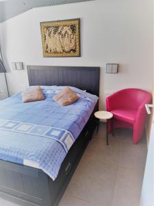 a bedroom with a bed and a pink chair at B&B Aalsters genot in Aalst