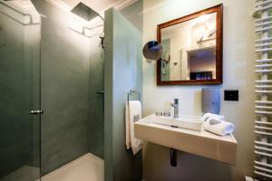 a bathroom with a sink and a shower and a mirror at Home Hotel Arosa in Arosa