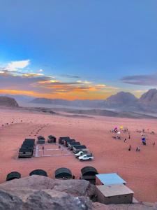 a desert with a group of tents and cars in the desert at Wadi Rum Starlight Camp in Wadi Rum