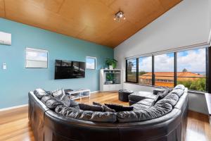 a living room with a leather couch and a tv at Beachside at Margaret River - Spacious Family Beach House in Exclusive Prevelly Location in Prevelly