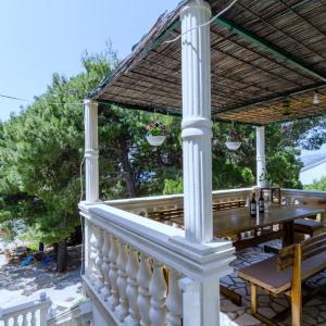 a porch with a wooden table and a pergola at Apartments Villa Dingač in Gornji Dingač