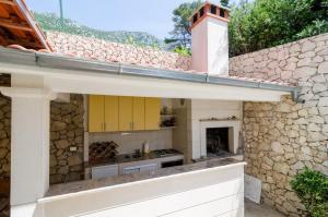 an outdoor kitchen with yellow cabinets and a stone wall at Apartments Villa Dingač in Gornji Dingač