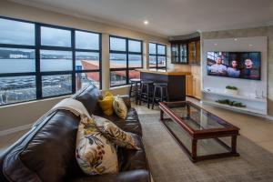 a living room with a leather couch and a television at Stay at The Point - Peaceful Plentiful Penthouse in Durban