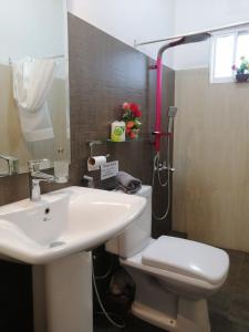 a bathroom with a white toilet and a sink at Le Petit Hotel & Restaurant in Negombo