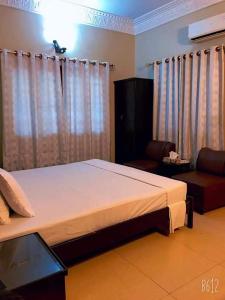 a bedroom with a large bed and a couch at Cosy Inn Guest House Karachi in Karachi