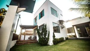 una casa blanca con césped delante en Viamar kitnet en Cumuruxatiba