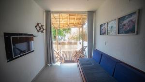 a living room with a blue couch and a television at Viamar kitnet in Cumuruxatiba