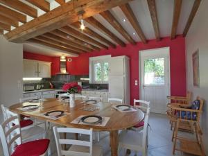 una cucina con tavolo in legno e pareti rosse di Gîte Juvigny-Val-d'Andaine, 5 pièces, 9 personnes - FR-1-497-115 a Saint-Denis-de-Villenette