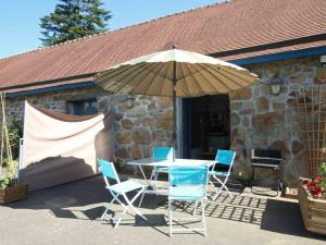 einen Tisch und Stühle unter einem Sonnenschirm auf einer Terrasse in der Unterkunft Gîte Sainte-Honorine-la-Guillaume, 2 pièces, 2 personnes - FR-1-497-4 in Sainte-Honorine-la-Guillaume