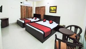a hotel room with two beds and a table at Hotel Supreme in Sylhet