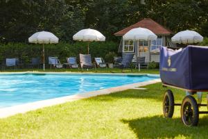 - une piscine avec des chaises, des parasols et une voiturette à côté dans l'établissement Chateau d'Audrieu, à Audrieu