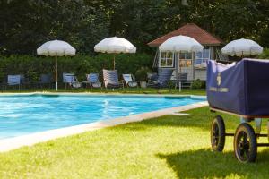 ein Pool mit Stühlen und Sonnenschirmen und ein Wagen daneben in der Unterkunft Chateau d'Audrieu in Audrieu