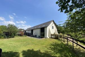 un granero blanco con una valla y un patio en Lower Curscombe Barn - Beautiful 400-year-old threshing barn. Pet-friendly., en Buckerell