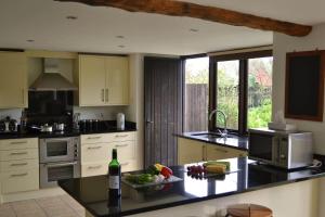 a kitchen with a counter with a bottle of wine at Lower Curscombe Barn - Beautiful 400-year-old threshing barn. Pet-friendly. in Buckerell