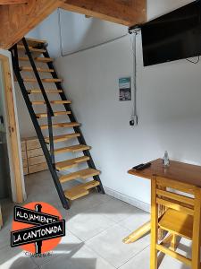 escalera de madera en una habitación con mesa y TV en La Cantonada, alojamiento turístico, Caviahue en Caviahue