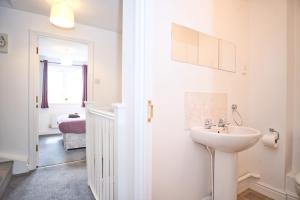 a white bathroom with a sink and a bedroom at St Katherines House - by TJ Serviced Property in Peterborough