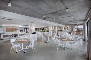 Bluewater Bay Sunrise Hotel في Amsterdamhoek: غرفة طعام مع طاولات وكراسي بيضاء