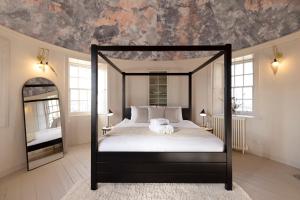 a bedroom with a black canopy bed with a mirror at JOIVY Observatory House & Apartment in Edinburgh