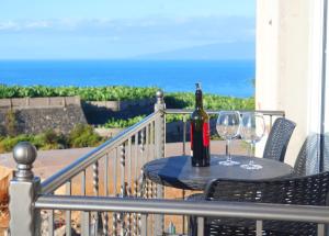 Una botella de vino y dos copas en una mesa en un balcón. en Casa Tranquila, en Playa de San Juan