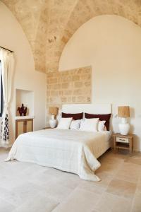 a bedroom with a large white bed with a stone ceiling at Masseria Calderisi in Savelletri di Fasano