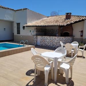 un patio con una mesa blanca y sillas junto a una piscina en Hotel Terra Mater, en Porto Seguro