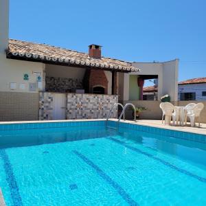 a swimming pool with two chairs and a house at Hotel Terra Mater in Porto Seguro