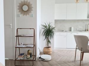 a white kitchen with a shelf and a plant at Royal Sand Apartment in Gdańsk +6 photos