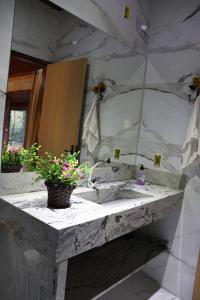 Un baño con lavabo de mármol y espejo. en Chalé da Lua - Parte Alta Parque Nacional de Itatiaia, en Itamonte