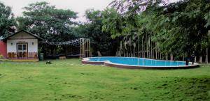 a swimming pool in a yard next to a house at Aranyagiri Countryside Resort, Near Pune in Pune