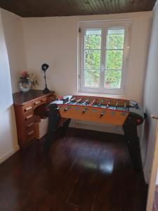 À flanc de colline في Cormeilles: طاولة ألعاب في غرفة مع مكتب ونافذة