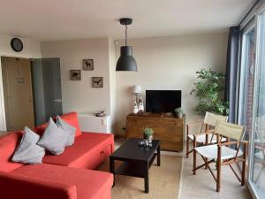 ein Wohnzimmer mit einem roten Sofa und einem TV in der Unterkunft Brise De Mer in Nieuwpoort